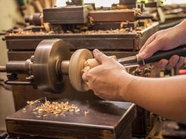 Manos trabajando en el torno durante los talleres de torneado de madera